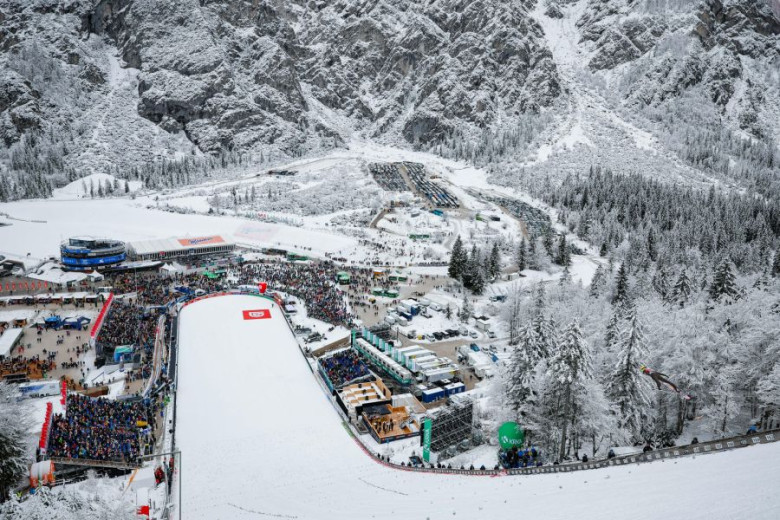 View from the ski jumping hill in Planica over the snowy landscape and the crowd of fans at the landing area.