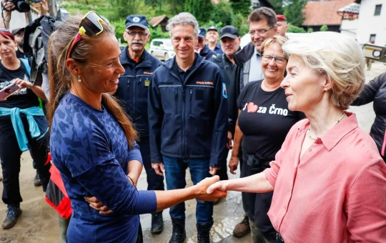 The European Commissioner talks to Tina Maze and shakes her hand. Premier Robert Golob and other officials are standing in the background.