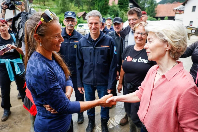 The European Commissioner talks to Tina Maze and shakes her hand. Premier Robert Golob and other officials are standing in the background.