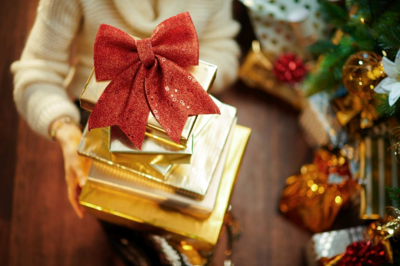 A woman hands are holding many gifts in gold paper