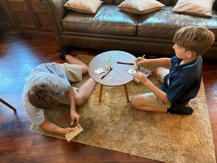 Two boys are sitting on the floor and make decorations for the christmas tree.