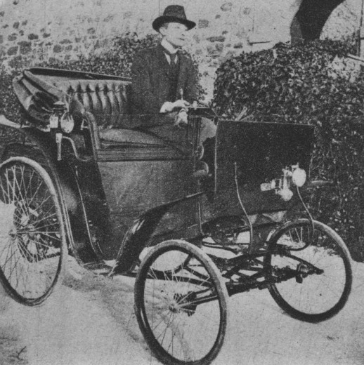 A man with the hat and black suit in the old car wich is looking like a carriage.