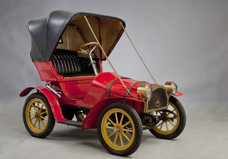 A red car with the black roof in the form of carriage.