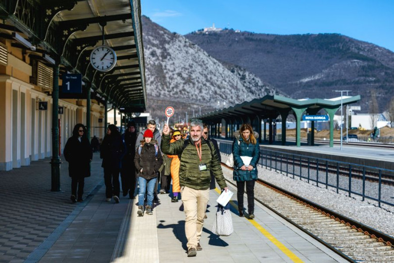 A man leading a  group of people on a tour at the train station