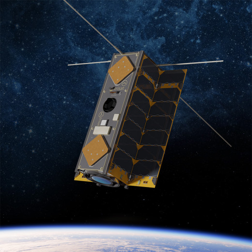 Nanosatelit v orbiti nad Zemljo, z vidnimi sončnimi celicami in antenami.