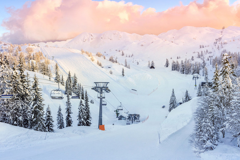Snow-covered ski slope with a chairlift and snowy spruces at in the mountains.