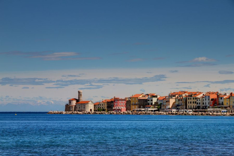 View of the city of Piran  from the sea with the old City Walls on the hill in the background.