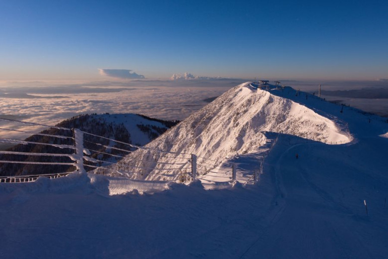 A snowy mountain ridge with a sea of fog in the valley in the background