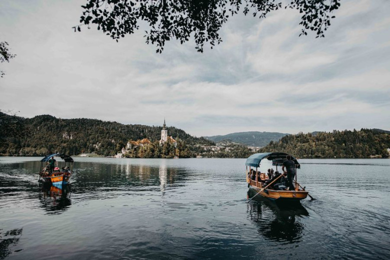 Lake Bled with two traditional wooden boats with the church on the island in the background.