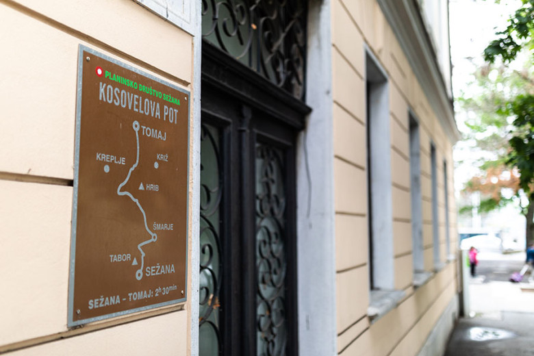 Metal sign with a walking route map mounted on a building wall.