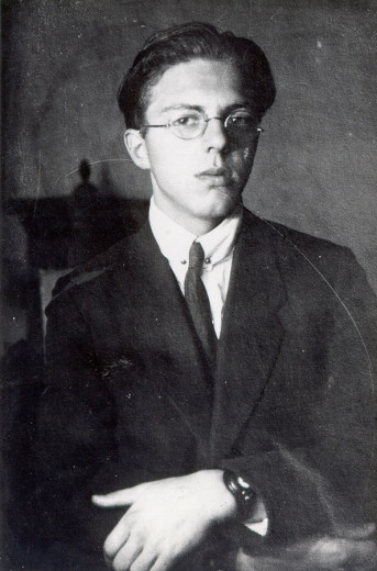 Black-and-white portrait of a young man wearing glasses and a suit.