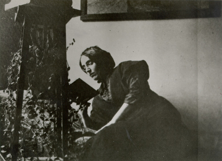 Black-and-white photograph of a woman sitting and reading a book.