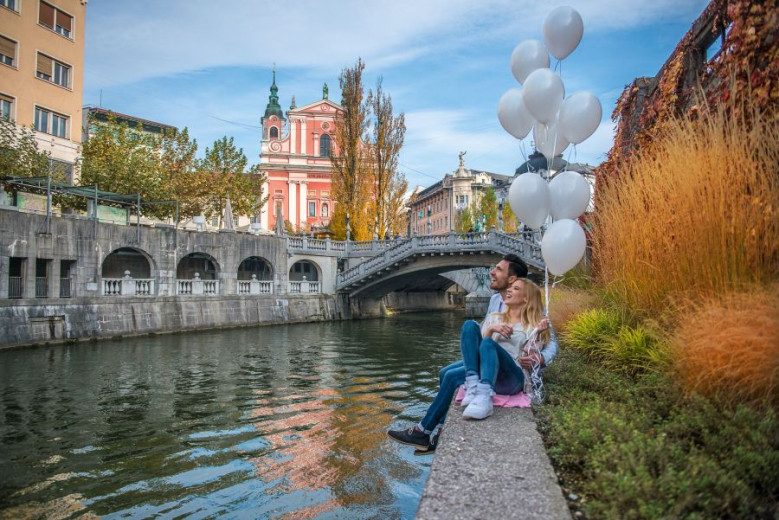 Couple is sitting at the bank of the river Ljubljanica.