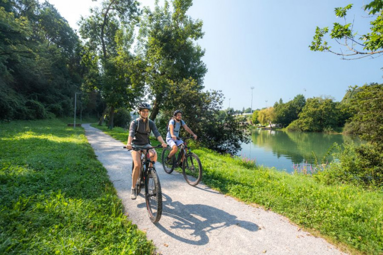 Moški in ženska kolesarita ob reki Krki.