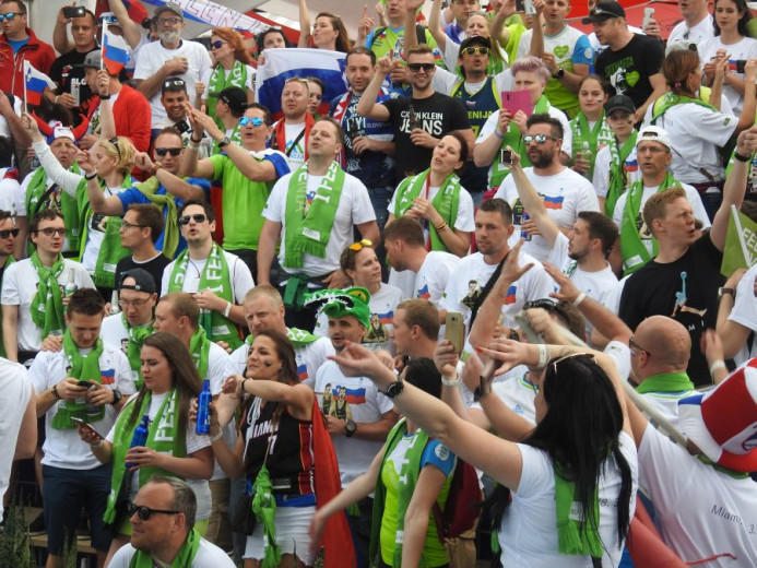 A group of fans with green I feel Slovenia scarves.