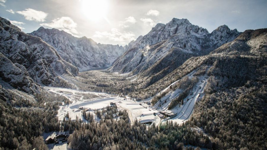 A snow-covered valley with ski jumps surrounded by mountains. 