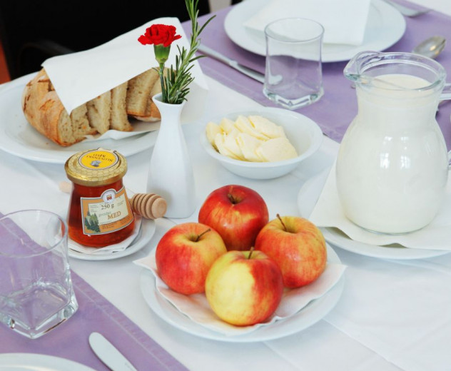 Kruh, maslo, med, mleko in jabolko na mizi