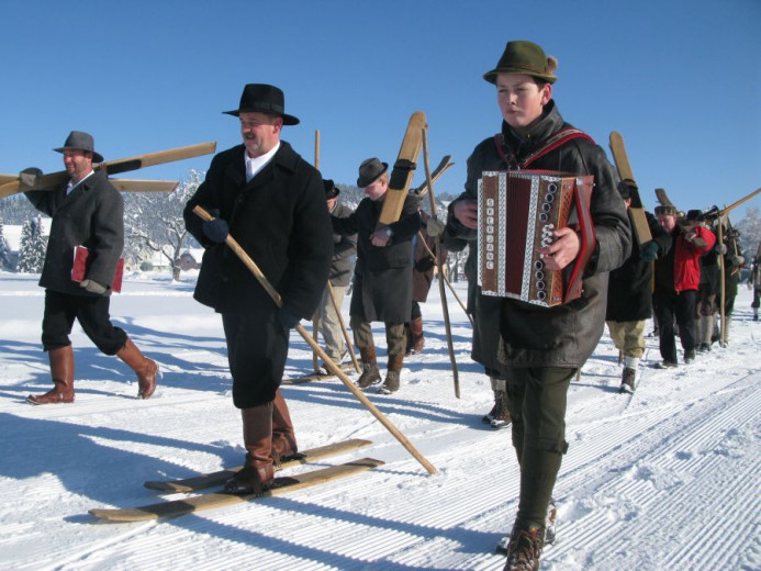 Men on wooden skis. A man playing accordion. 
