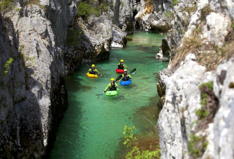 Kayakers on a river flowing through a gorge.