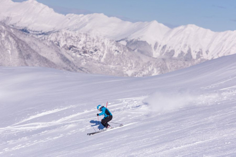 A skier in the middle of the white slopes.