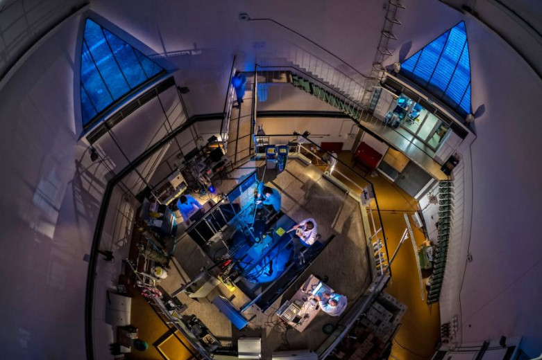 Overhead view of the TRIGA research nuclear reactor with researchers on the reactor platform and the reactor core visible beneath the water.