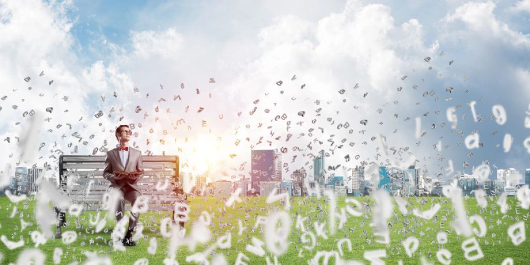 A man sits on a park bench holding a book, looking upwards amidst floating letters against a blurred city backdrop.