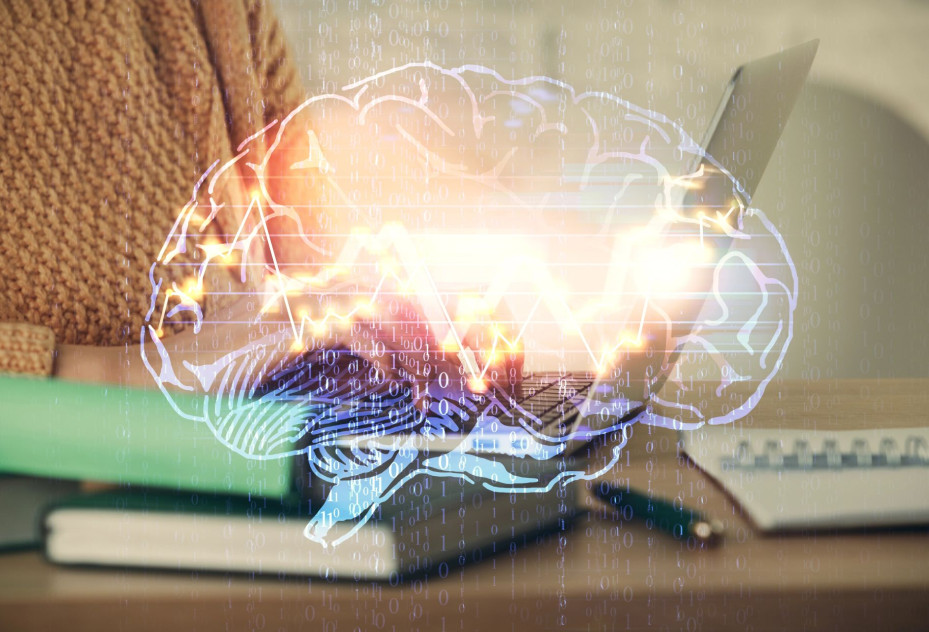 Close-up of person using laptop with a luminous, semi-transparent drawing of a human brain..