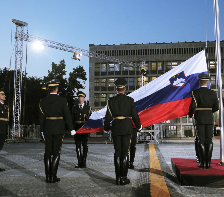 Pripadniki častne straže sodelujejo pri dvigu slovenske zastave na drogu na Trgu republike pred stavbo parlamenta.