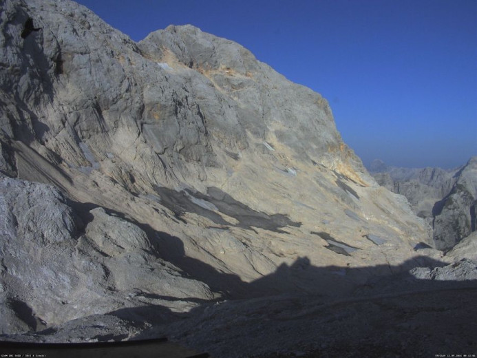 A photo of a steep mountain slope covered in some parts with small patches of ice.
