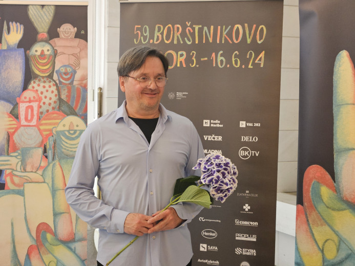 Igralec Branko Šturbej v rokah drži rožo, v ozadju napis o Borštnikovem srečanju.