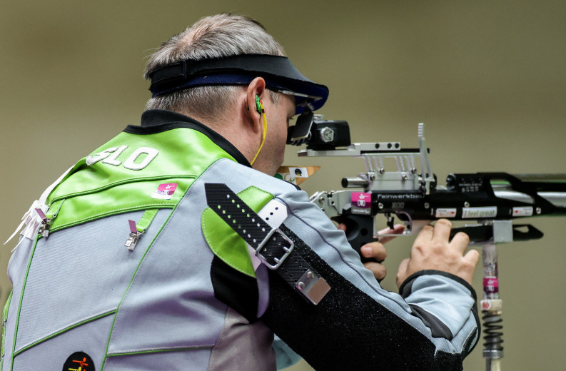 A goggle-wearing Tiršek shoots an air rifle.