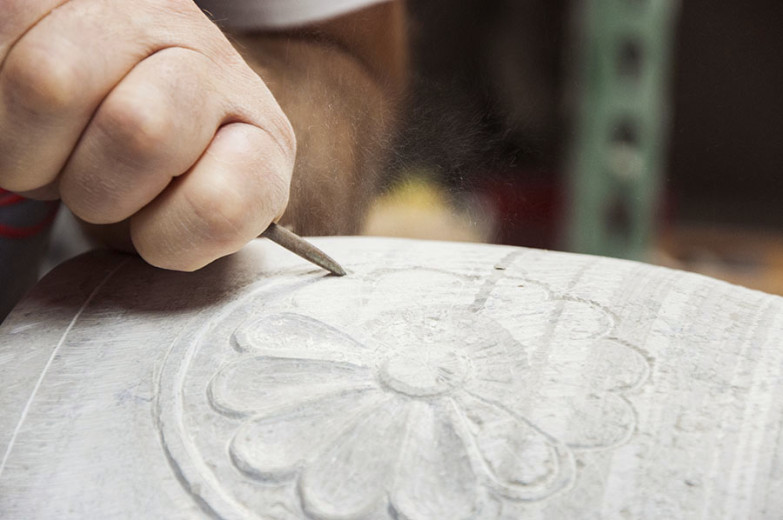 A stonemason shapes a stone with a chisel.