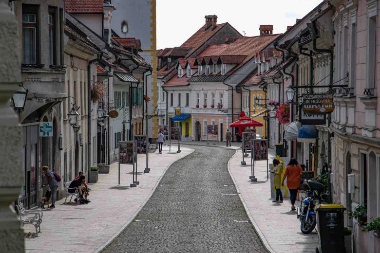 A paved street in the old town of Kamnik, and some people walking on the sidewalks.