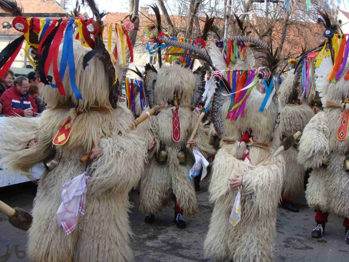 Kurents are walking on the street in a procession.