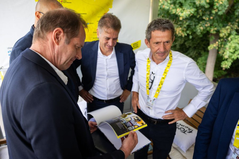This photo shows slovene prime minister Rober Golob and organizers of the Tour de France standing together and looking at the letter of intent to organize the start of the Tour in Slovenia. 