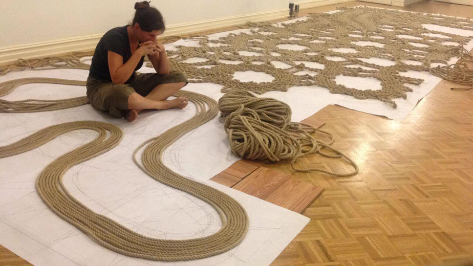 Manca Ahlin sits on the floor surrounded by a cobbler's installation.