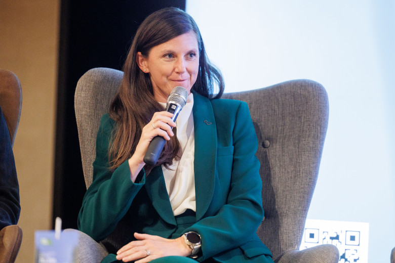 Melanja Korošec sits in an armchair and speaks into a hand-held microphone.