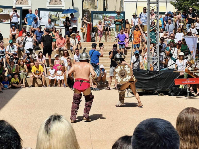 Two gladiators fighting in an arena with many spectators.