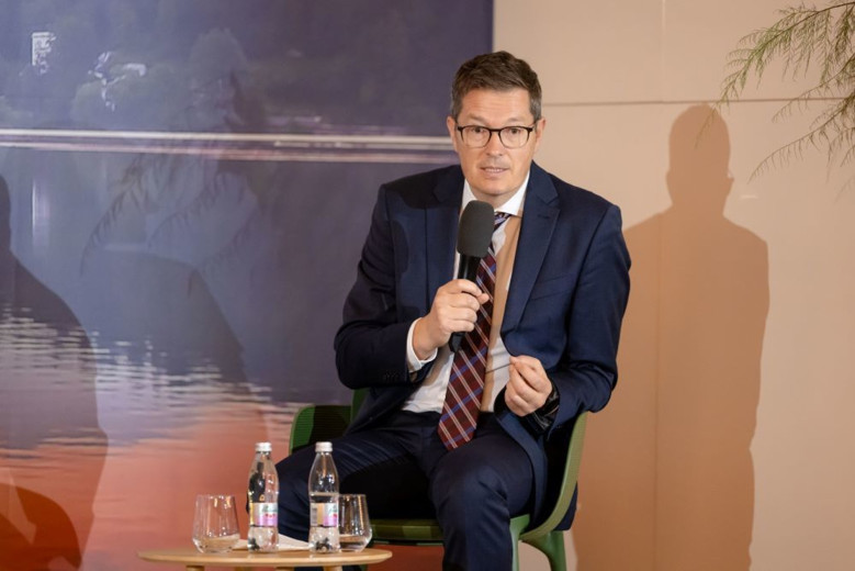 Tobias Pogorevc sits at his desk, microphone in hand.