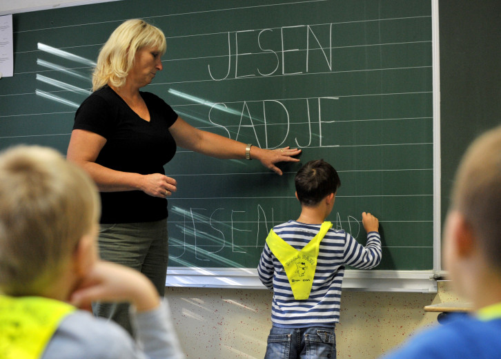 A teacher and a first-grader in front of the school blackboard.