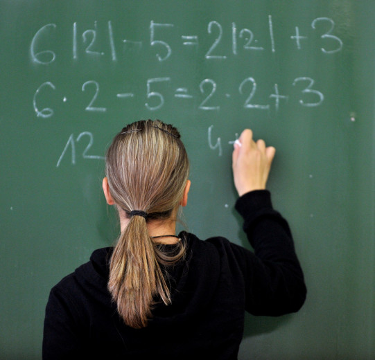 A pupil writes numbers on the school blackboard.