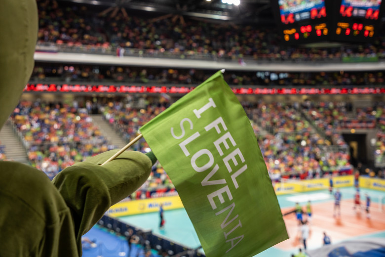 In the foreground, the I Feel Slovenia flag, in the background, fans at the volleyball championship in Stožice.