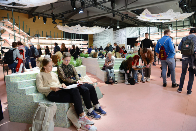 The Slovenian Pavilion, visitors sit in armchairs next to bookshelves.