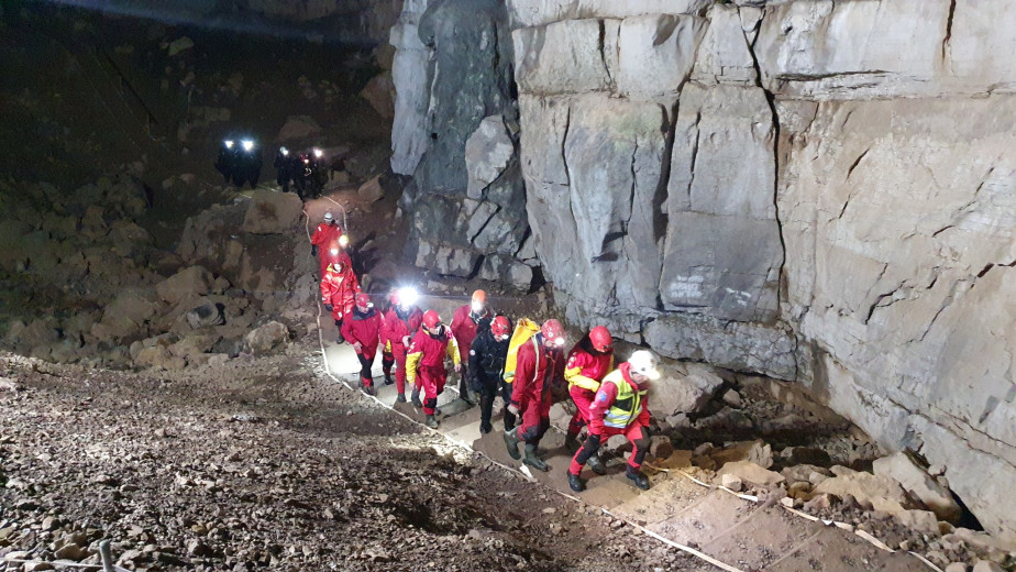 Kolona reševalcev ob steni v jami.