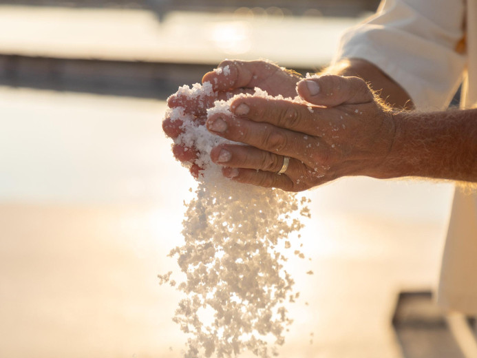 Moške roke spuščajo sol med dlanmi.