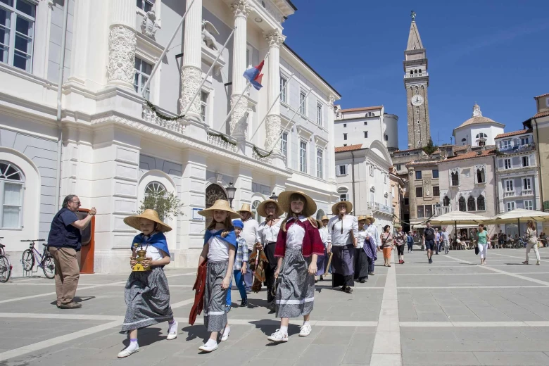A crowd of kids is dressed in ancient salt-mining clothes with big hats in Tartini Square.