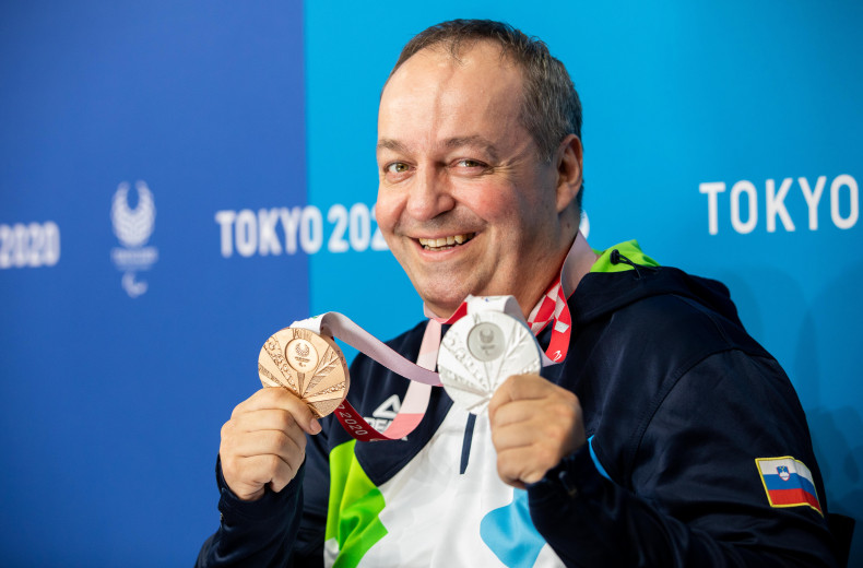 Tiršek holds two medals from Tokyo.