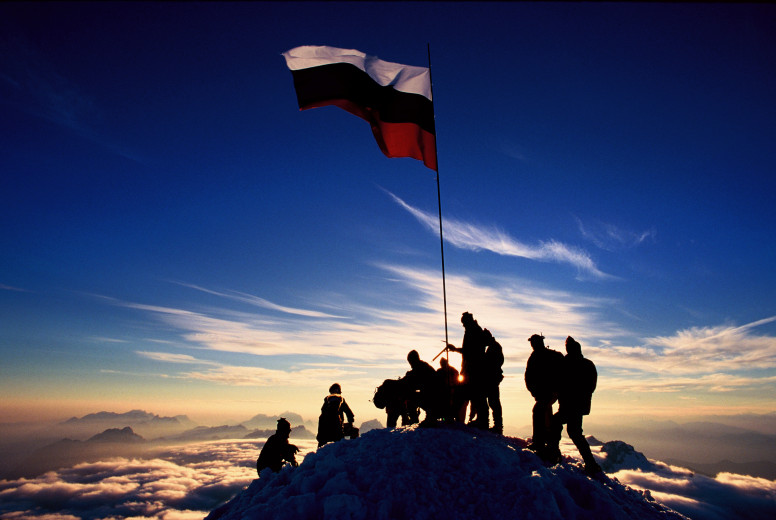 Mountain rescuers unfurl the Slovenian flag at the top of Triglav.