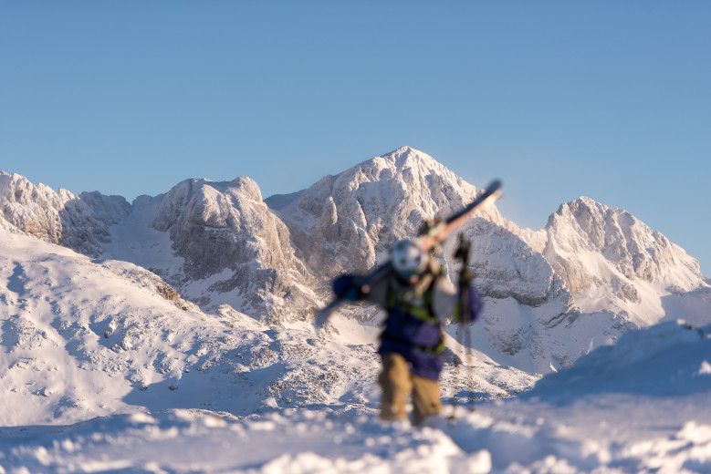 A skier carries skis on his shoulder.