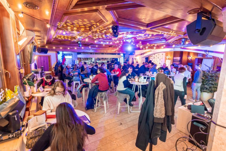 Interior of the Slovenia house. A lively venue with a wooden interior, where guests sit at high round tables and chat.